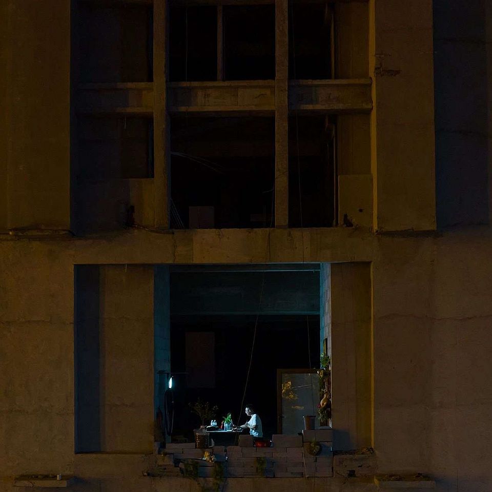 someone sitting at his laptop in the dark in a several stories house without the window